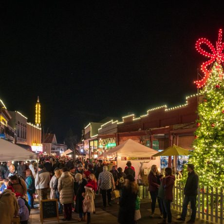 group of people walking along a shopping mall next to a Christmas tree