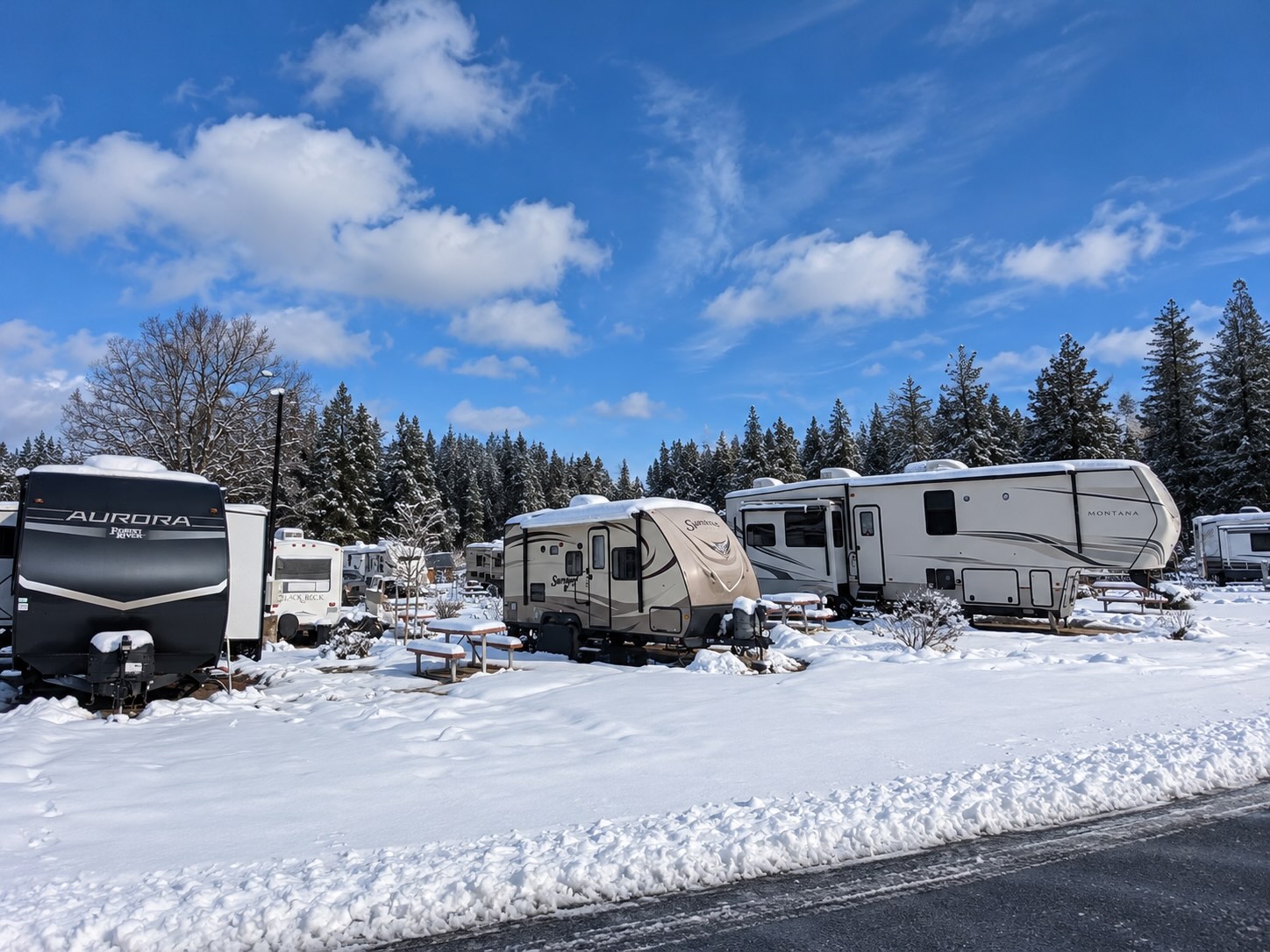 RVs in a snowy campground beneath blue skies
